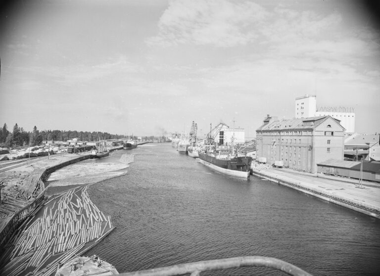 Toppilansalmea vuodelta 1957, vedessä on paljon tukkeja, vasemmalla näkyy Vaasan myllyn rakennukset, satamassa ainakin kuusi laivaa.